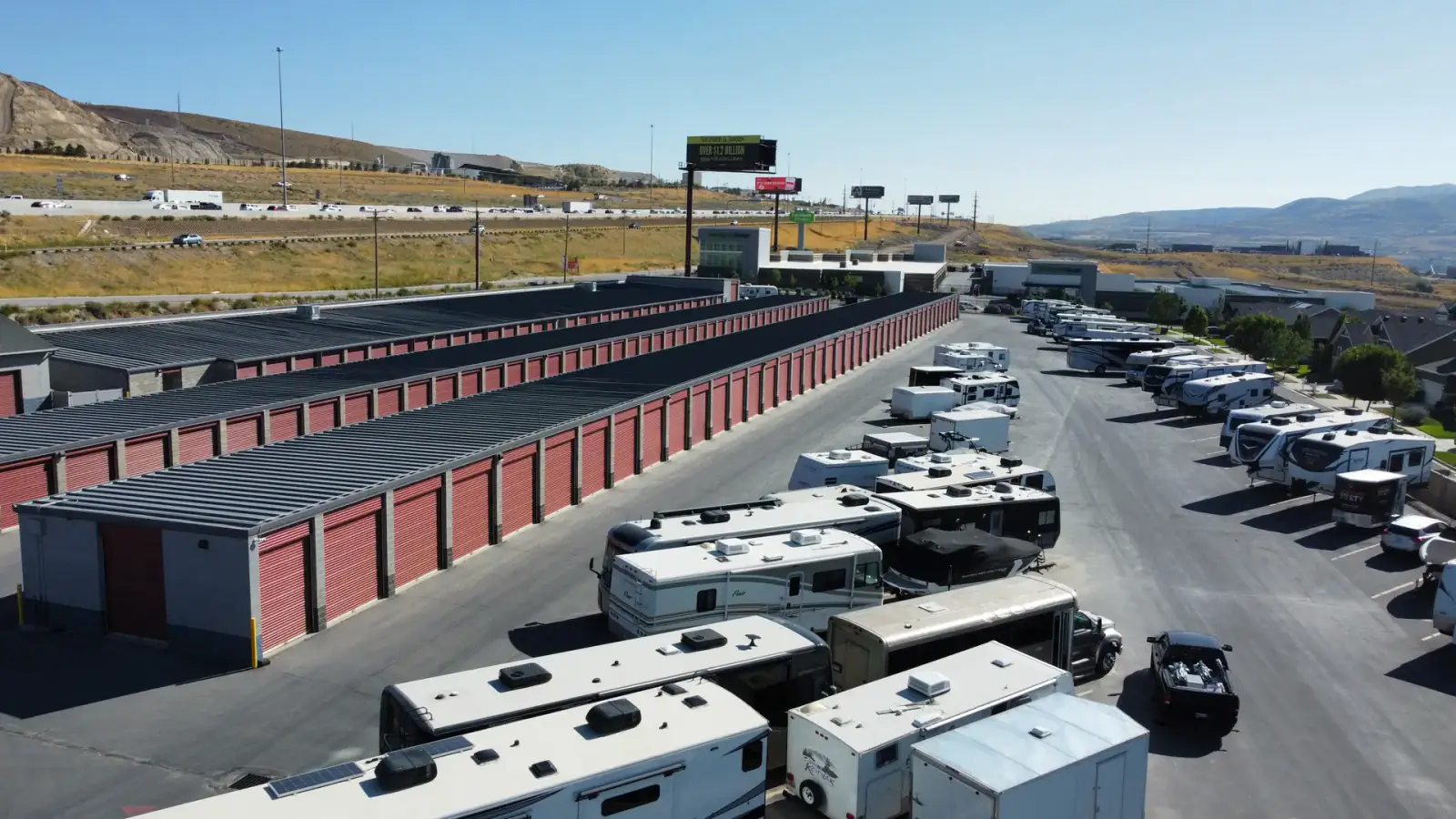 RVs and boats parked along a Wasatch Structures boat and RV storage building with mountains behind